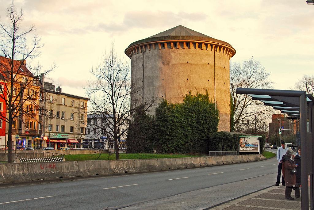 DSC_6328g.jpg - Universitätsstr.  [de]Der Rundbunker steht zwar voll im Weg, dafür inzwischen aber unter Denkmalschutz. Die Straße musste geteilt werden und macht mit diesen beiden Fahrspuren heute eine Schleife um den Bunker - dafür wurde eine ganze Hausreihe abgerissen, wo heute die Bushaltestelle ist.[en]The round air raid shelter stands totally in the way therefore but is a Listed Building today. The road is divided with these two lanes making a bend around the Bunker. Where the bus stop is now used to be a row of houses which were pulled down to get enough space.