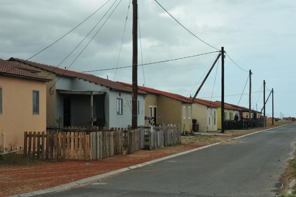 101_1002.JPG - -Township of Delft. [en]The "better" black middle class lives are often in such a two-room bungalows. Many of them can just afford even simpler  houses (huts) with a single room: living room, bedroom, nursery, kitchen..., or it is not even enough for that.[de]Die "bessere" schwarze Mittelschicht wohnt oft in solchen Zwei-Raum-Bungalows. Oft gibt es aber nur Häuser (Baracken) mit einem einzigen Zimmer: Wohnraum, Schafraum, Kinderzimmer, Küche..., oder es reicht nicht mal dafür.