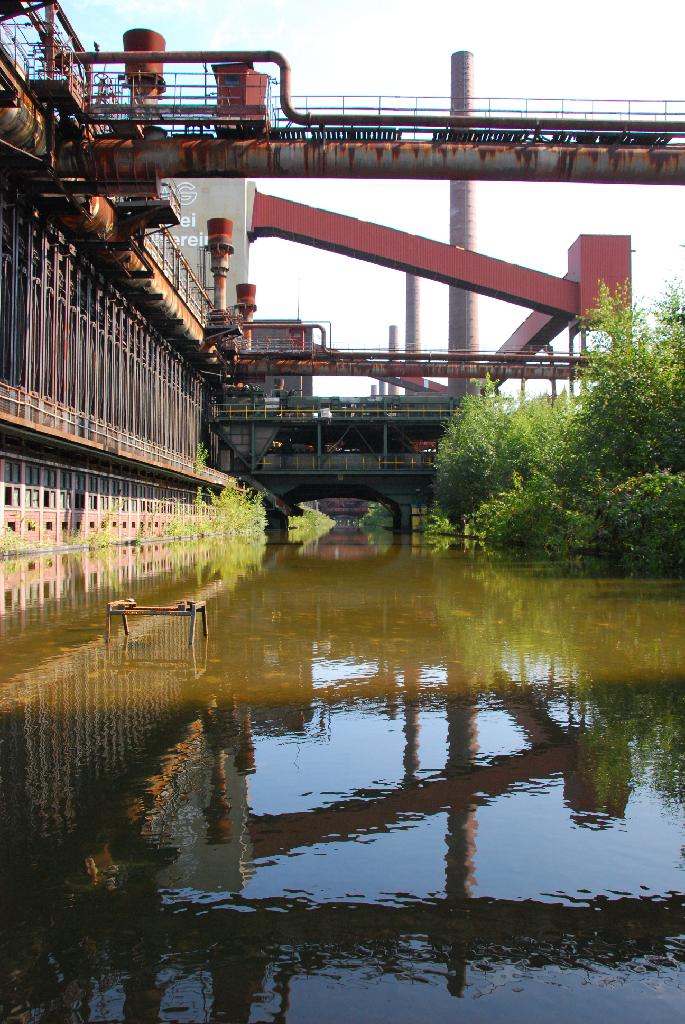 DSC_3762.JPG - [de]Sobald der Koks fertig gegart war, wurde er aus den Ofenbatterien in spezielle Transportwagen ausgestoßen und dann zum "Löschen" mit Wasser gefahren. Ungelöscht wäre der glühende Koks ansonsten durch den Luftsauerstoff vollständig  verbrannt. - In dem Becken des ehemaligen  Druckmaschinengleises, auf dem der Wagen entlangfuhr, staut sich heute das Regenwasser 