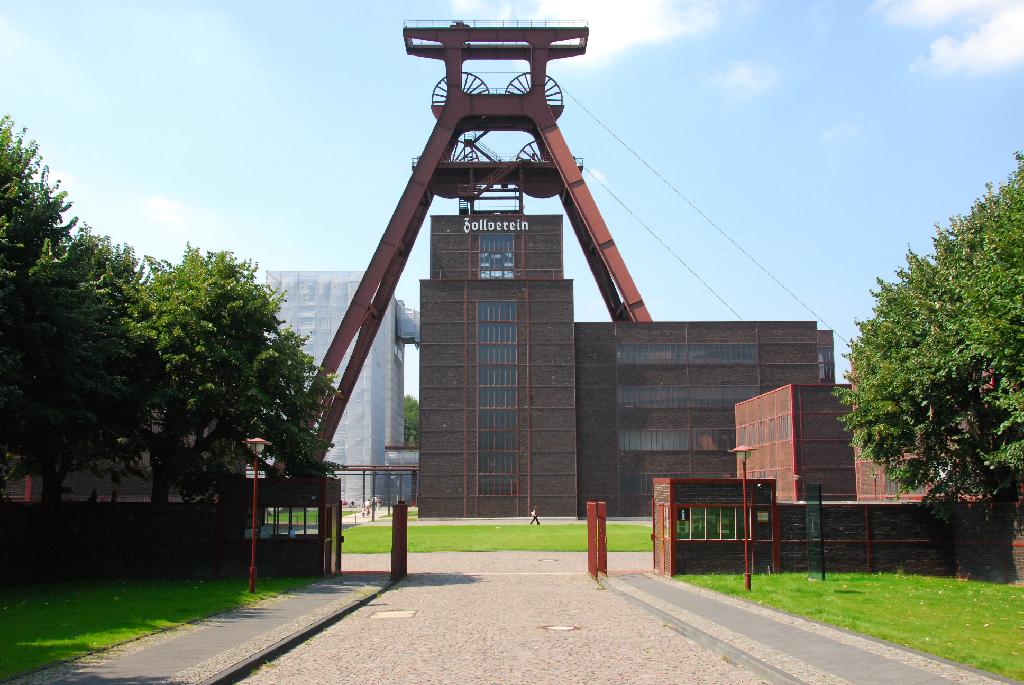DSC_3884.JPG - [de]Der Haupteingang der ehemaligen Zeche Zollverein in Essen strahlt Ordnung, Selbstbewusstsein und Macht aus: eine eigentlich sehr dreckige Kohlenförderanlage stellt man sich anders vor. Aber hier wurde "Big Business" gemacht: riesige Investitionen und riesige Gewinne. Hier arbeiteten fast 5.000 Leute. Die Fördermenge lag bei 3 Mio Tonnen im Jahr, und eine riesige Kokerei war direkt angeschlossen. Die Gebäude sind dem damaligen Zeitgeschmack entsprechend zwar zweckmäßig, jedoch auch architektonisch ansprechend gestaltet - die Klinkerfassaden haben keinerlei funktionelle Aufgabe. Nicht umsonst nannte man die Bergbau- und Montan-Anlagen auch "Kathedralen". Die Zeche wurde erst Ende der 80er Jahre stillgelegt - gerade mal vor 20 Jahren. Heute ist sie Weltkulturerbe und Museum - und ein Stück deutsche Geschichte.[en]The main entrance to the former mining estate represents order, sovereignty  and power. Big business was made here, giant investments and giant wins. At its best time middle of the last century more than 5,000 people used to work just here at  "Zollverein"  producing over 3 million tons of coal, and a coking plant was directly attached. The power of the mining companies indeed was represented by their buildings, which were called "cathedrals". - Now all this is history and was about to being forgotten: "Zollverein" was shut down in 1986, but thanks to public and private initiatives today it is an cultural event center, museum - and a World Heritage Site since 2001.